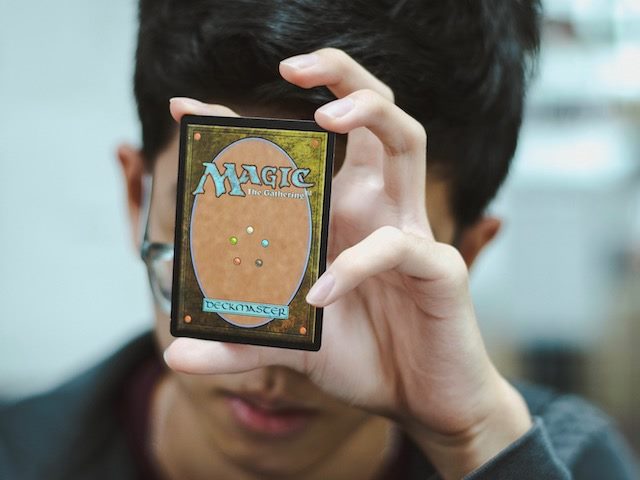 man holding magic card up against forehead