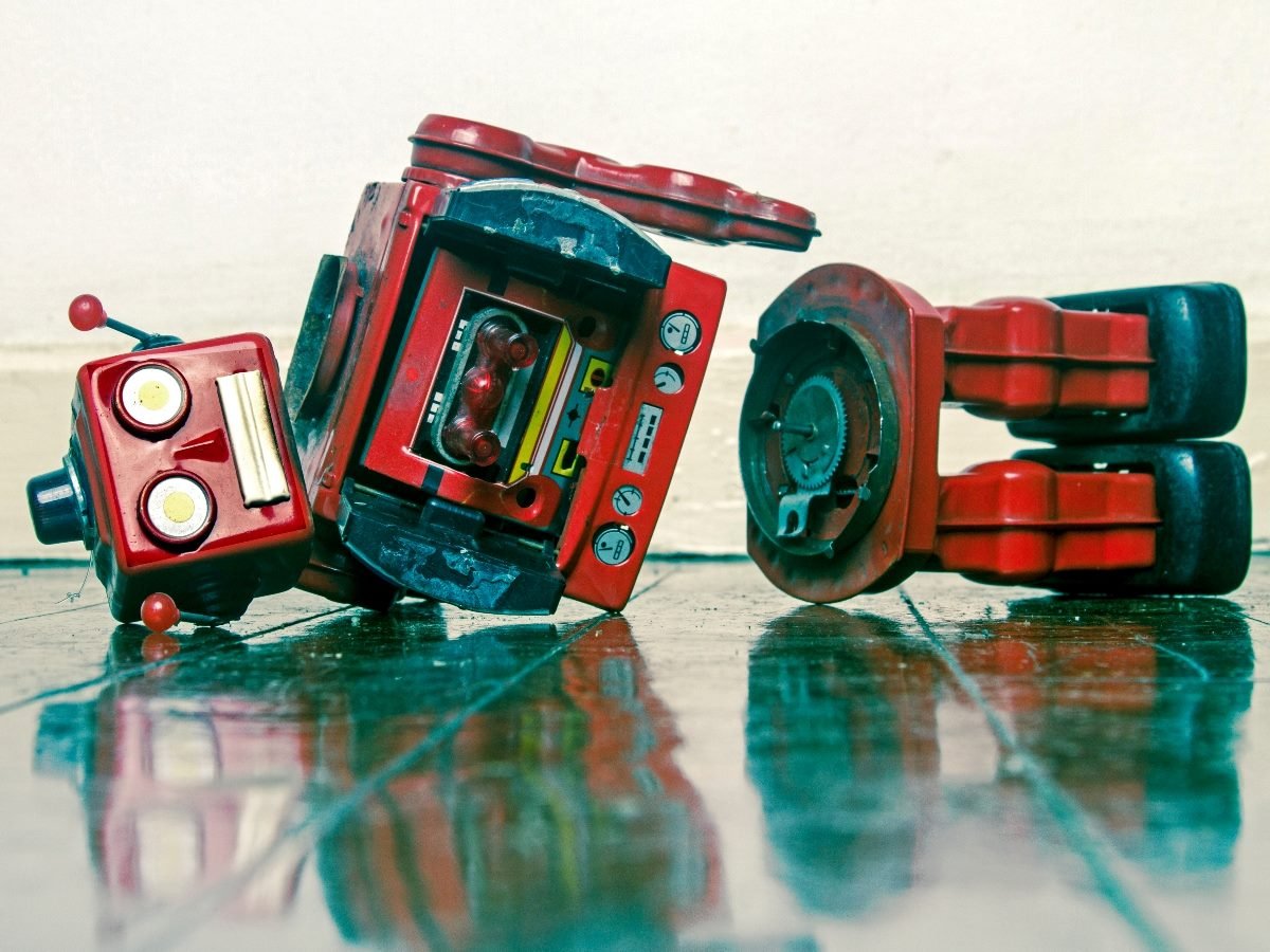 A broken vintage red toy robot lying on the floor, symbolizing the limitations of traditional chatbot-style AI.