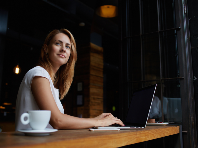 A woman working with her laptop remotely in a cafe.