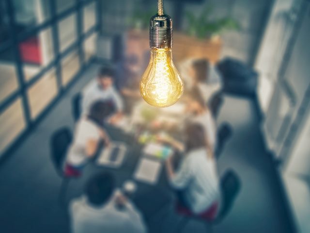 Lightbulb shining in the middle of a meeting 