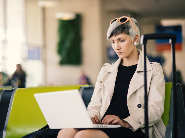 A person sitting at an airport and using a laptop 