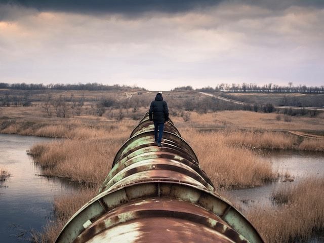 person walking on top of large pipe