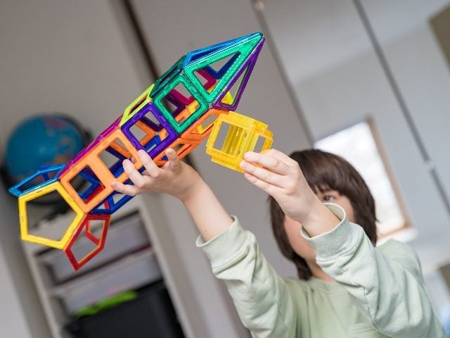 Child plays with a coloful magnetic building set  in a room in piece about customer experience strategies and composable modules. 