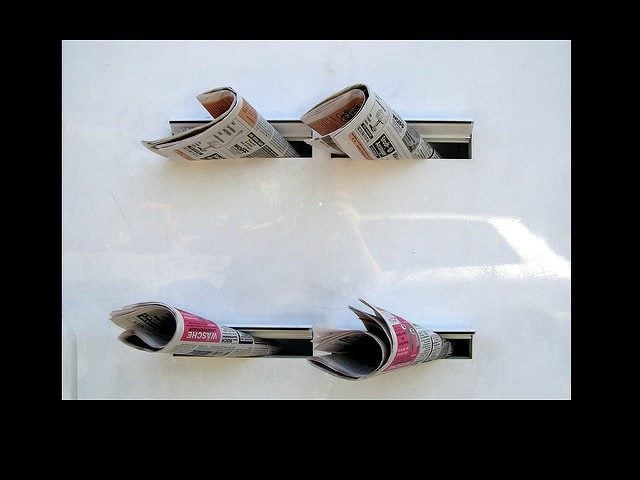 Four newspapers in mail slots.
