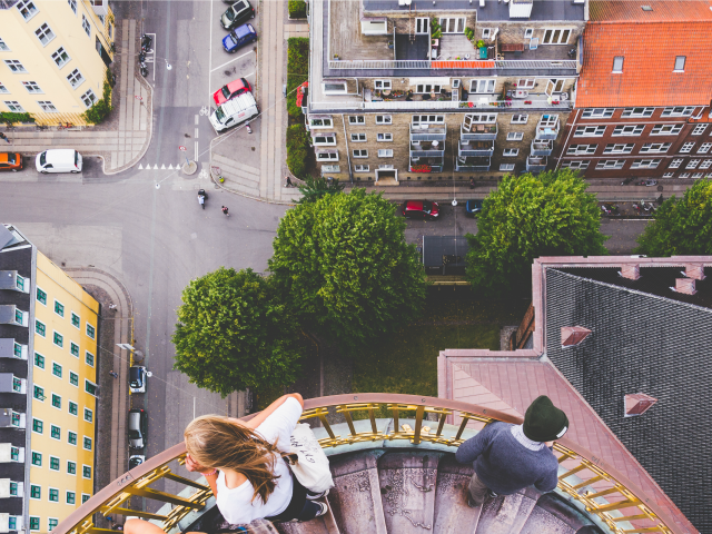 two people on a balcony looking down at people on the street