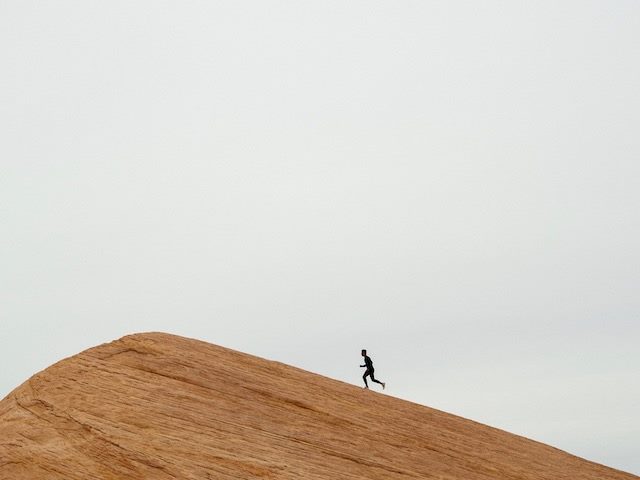 silhouette of a runner running uphill