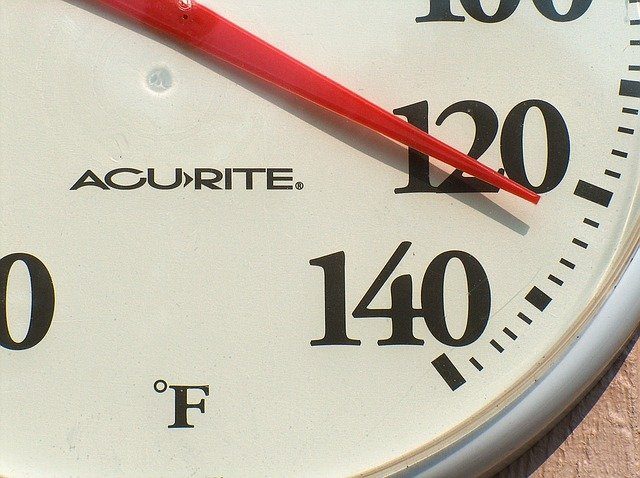 white circular outdoor thermometer showing summer heat temperature of 120 degrees fahrenheit