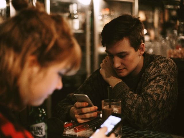 two friends reading on their cellphones