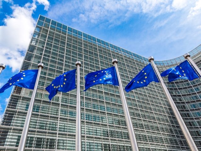 European Union flags with the backdrop of a European Union building in Brussels.