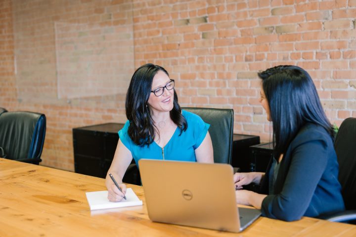 woman with teal shirt sitting beside woman in suit jacket