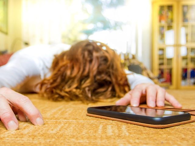 person laying on ground with cellphone in front of them