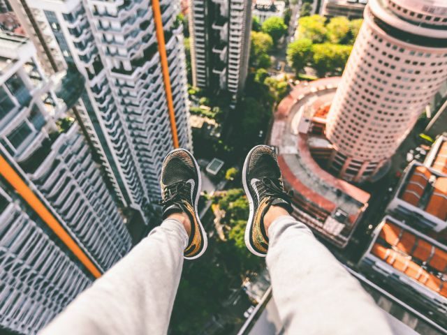 feet dangling over edge of skyscraper