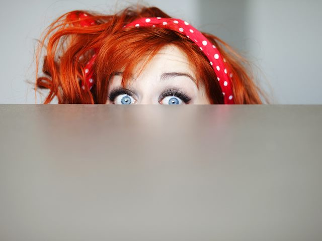 woman peeking out over an opaque screen