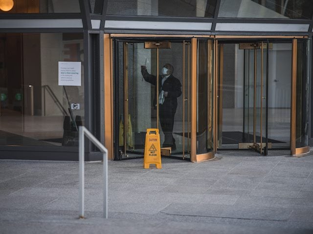 caution sign in front of a set of revolving doors