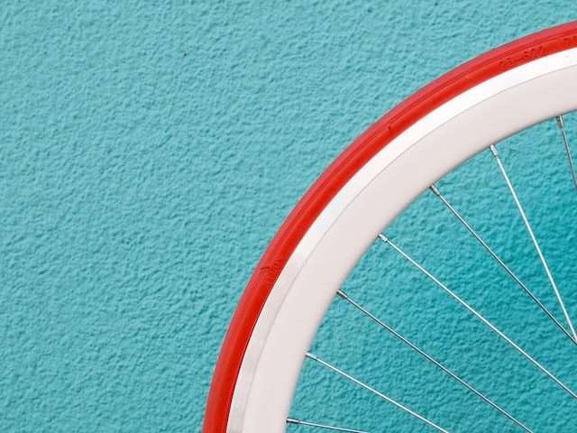 close up of a bicycle wheel against a turquoise wall