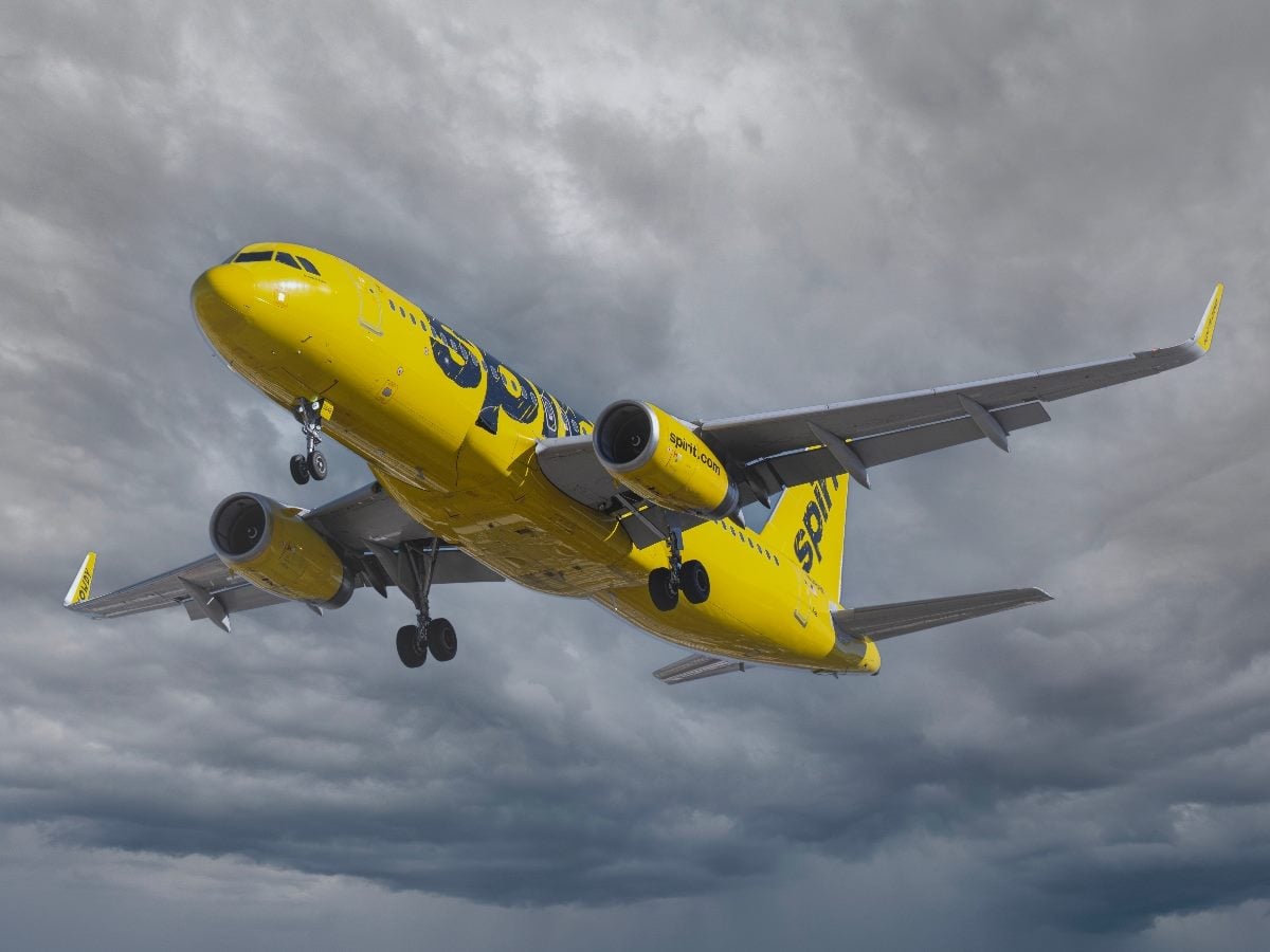 Spirit Airlines Airbus A320 aircraft descending for arrival at Harry Reid International Airport in Las Vegas on Nov. 23, 2024, flying beneath dark storm clouds with landing gear extended. The bright yellow aircraft contrasts sharply against the turbulent gray sky, visually reinforcing themes of operational pressure and instability associated with the airline’s customer experience challenges.