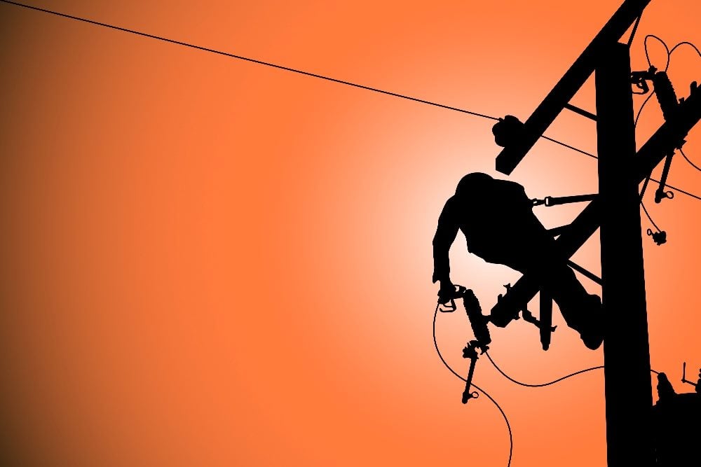The silhouette of a power line worker up high on a pole to fix a broken, disconnected line in piece about omnichannel customer service.