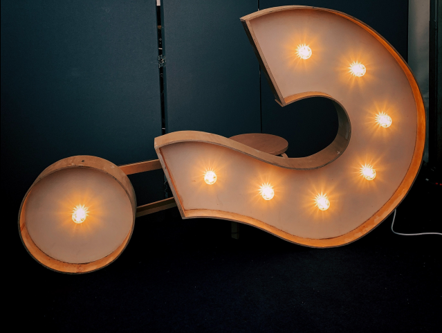 A question mark sign on its side, with lighted bulbs on a dark background - big question concept