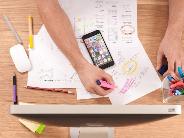 working on computer, phone and paper