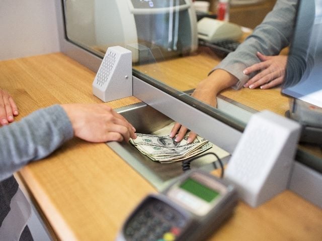 Clerk giving cash to customer at bank office.