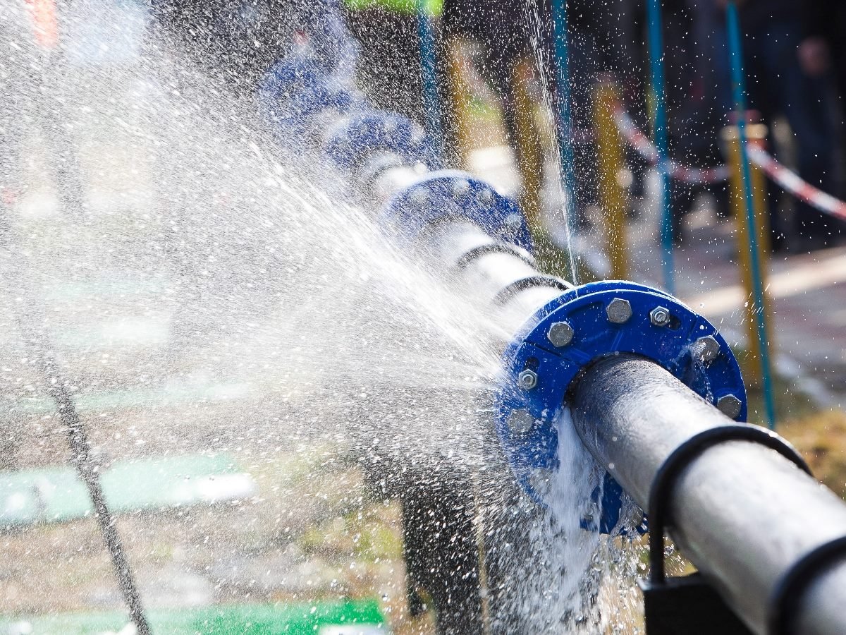 A leaking water pipe spraying water through loose joints, symbolizing cracks in a customer retention pipeline.