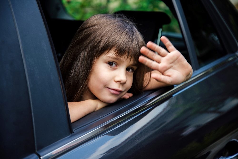 A child with bangs waves through the window of a blue car in piece about personalized marketing and cookes.