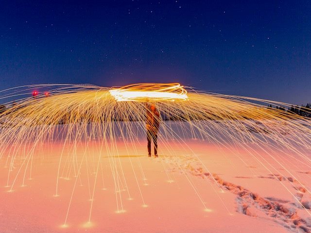 person dancing with fire, sparks shooting out