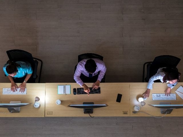 Top view of three customer care service agents working in a contact center. 