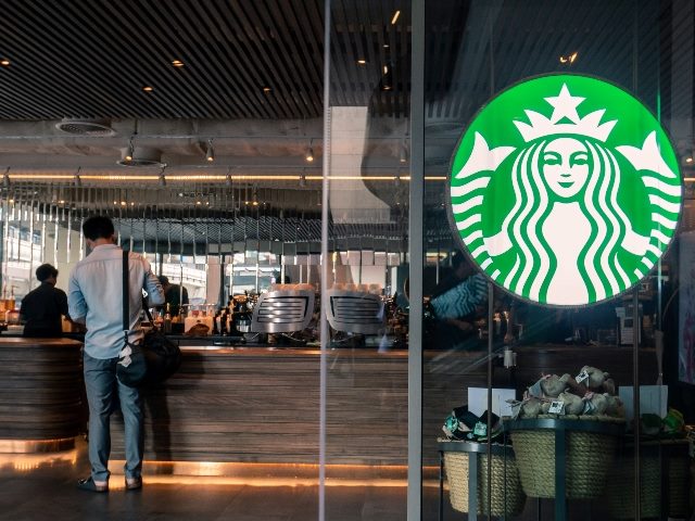 Starbucks coffee logo in front of the shop with people ordering. Starbucks is weathering a PR crisis, and there are lessons to be learned. 