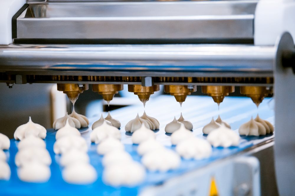 Cookie equipment, production line blue conveyor in confectionery factory with cookies being extruded in piece about automating customer service and the employee experience.