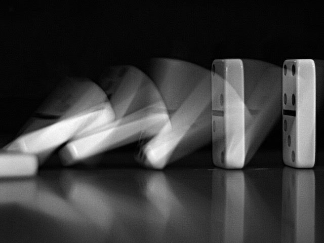 time lapse photo of lined up dominoes falling over