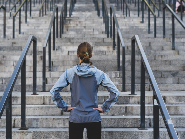A woman staring at a flight of stairs she is about to ascend for her exercise routine - challenges ahead concept