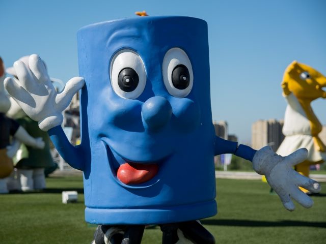 Close up shot of blue mascot character waving at camera.