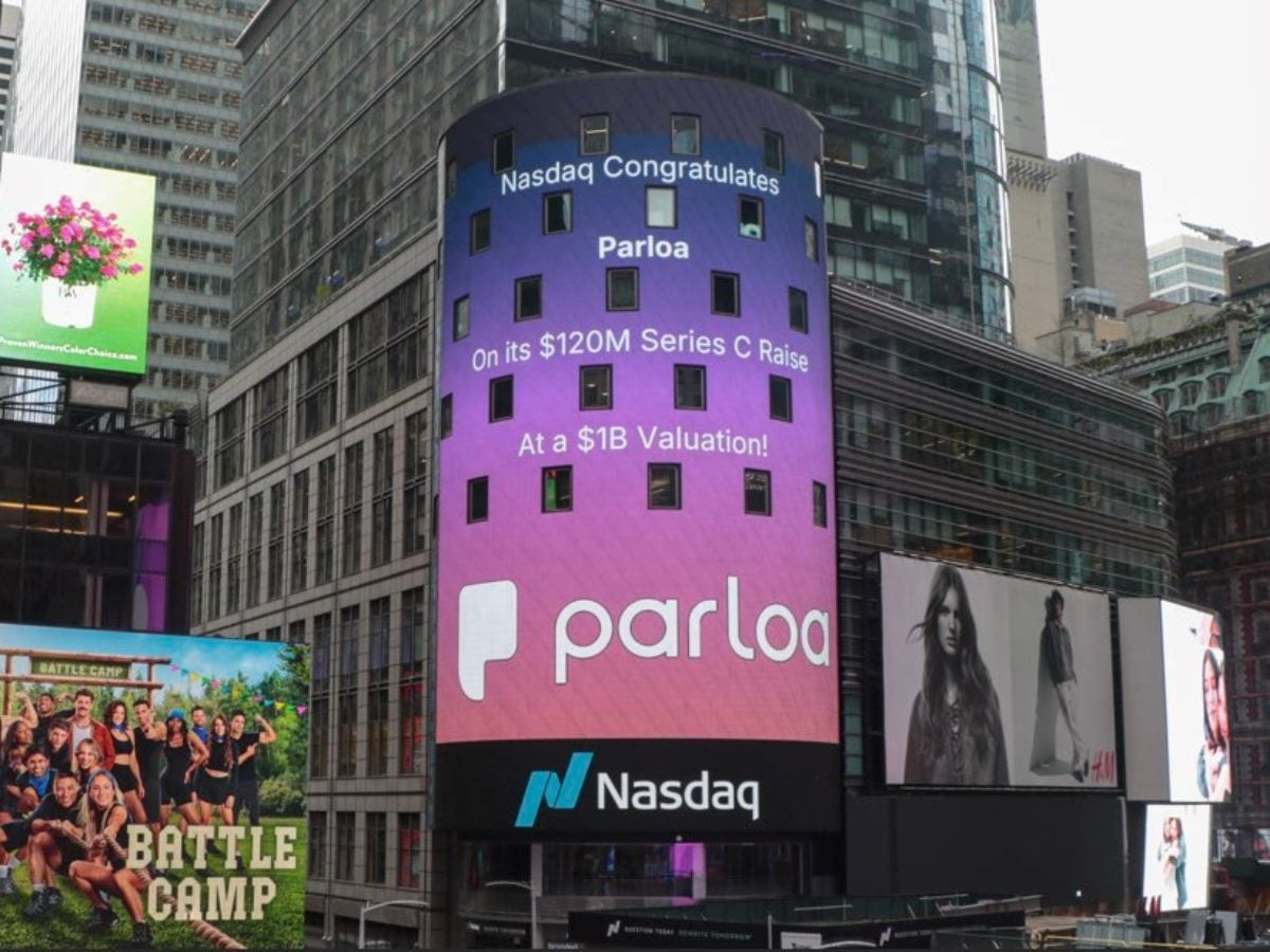 A large Nasdaq digital billboard in Times Square congratulates Parloa on its $120 million Series C funding round and $1 billion valuation, surrounded by other illuminated advertisements and high-rise buildings.