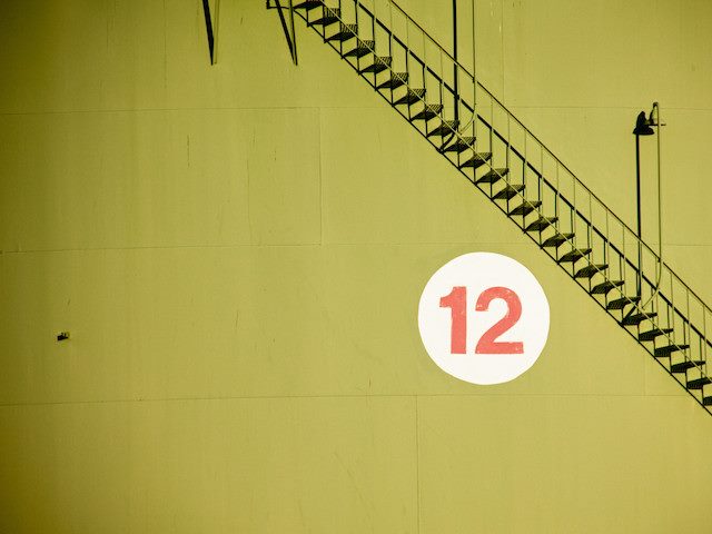 number 12 on chartreuse wall with metal staircase overhead
