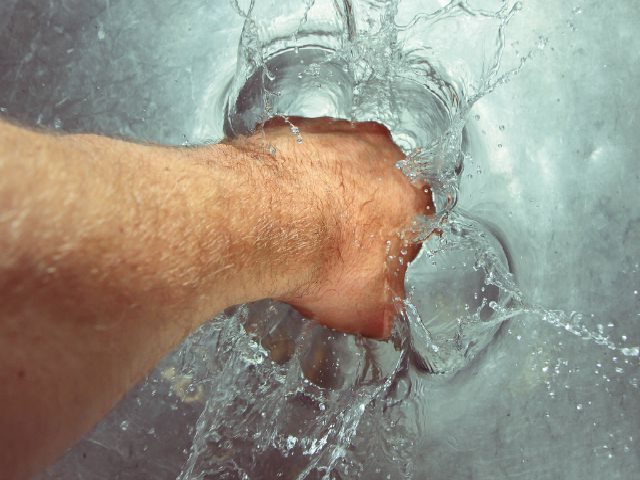 a man's hand breaking water