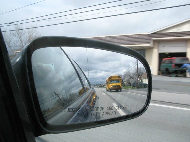 Rear-view mirror with a school bus in the rear.
