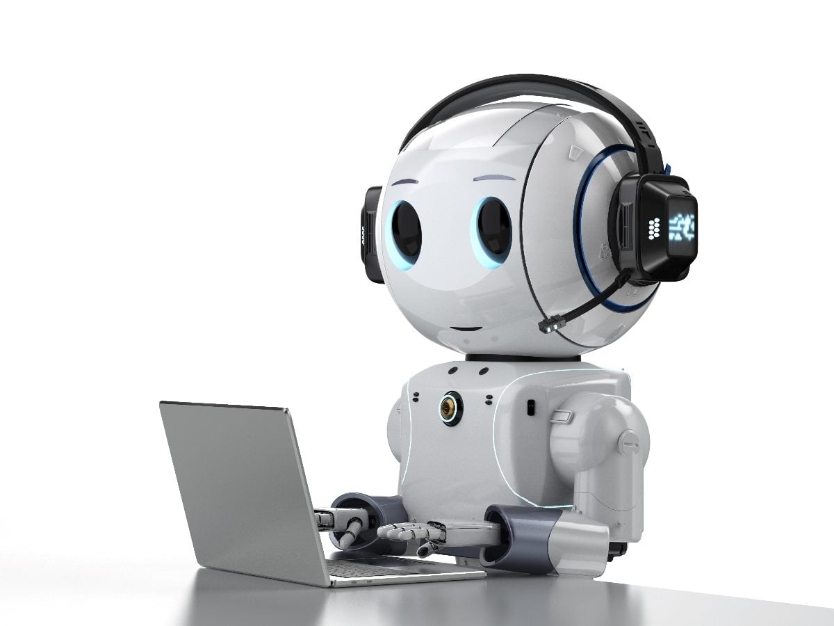 Illustration of a friendly white AI robot wearing a headset and microphone while working on a laptop computer. The robot has large blue-lit eyes and sits at a desk against a plain light gray background, suggesting an AI assistant, chatbot or autonomous digital agent performing tasks on behalf of a user.