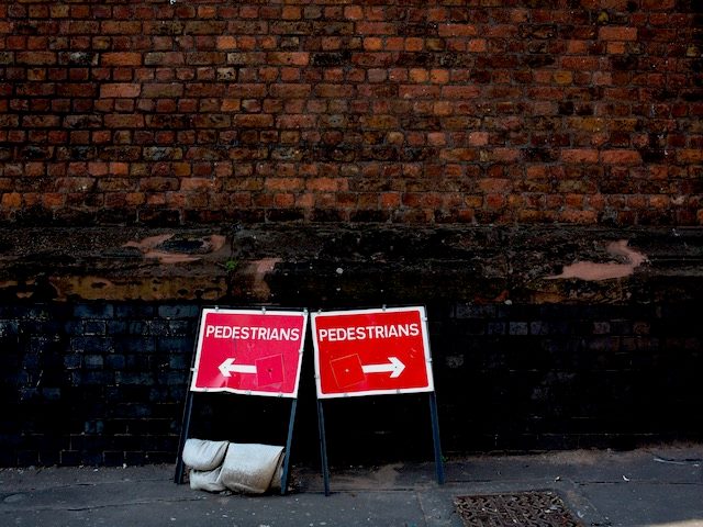 two pedestrian directional signs  next to each other pointing in opposite directions