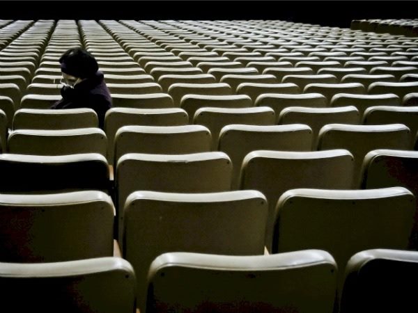 woman sitting among empty seats