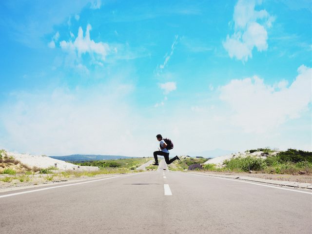 man jumping over the middle of the road dividing line