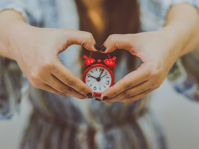 Woman holding an antique alarm clock in her hands - timezone collaboration concept