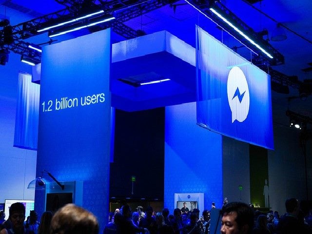 Scene at the Facebook Developer Conference F8. Sign that says "1.2 billion users" and another sign that says "Facebook Messenger"