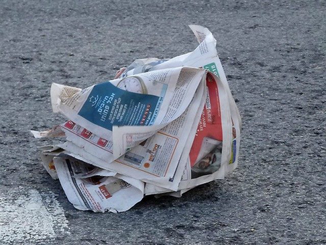 a newspaper blowing in the wind on the ground.
