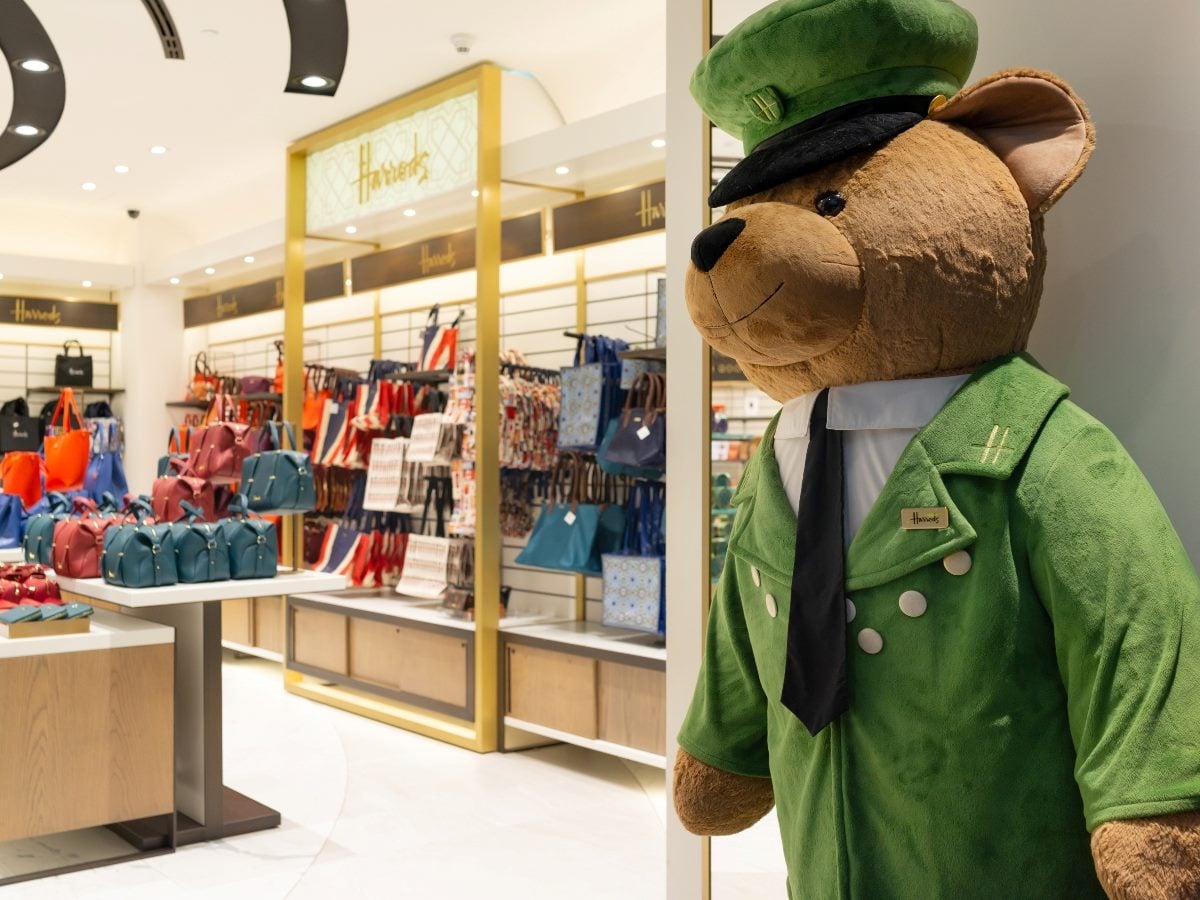 Harrods teddy bear mascot standing inside a Harrods store at Hamad International Airport in Doha, Qatar.