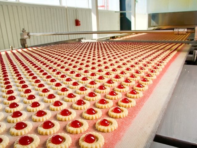 Factory production of red jelly filled cookies perfectly lined up row after row in story about AI Automation.