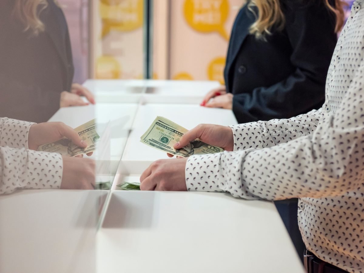 Customer handing over US dollar bills at a bank counter, illustrating financial transactions and customer experience in retail banking.