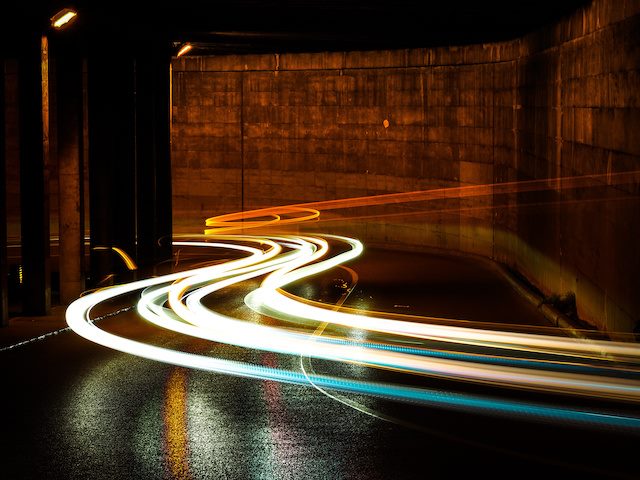 time lapse photograph of car headlights driving through a tunnel
