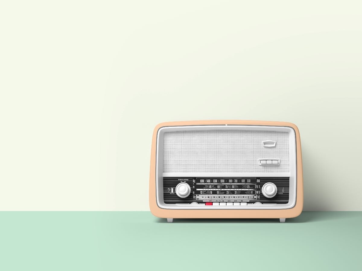 Minimalist image of a vintage beige tabletop radio with analog dials and AM/FM tuner, set against a soft green background, evoking classic broadcast-era audio advertising.
