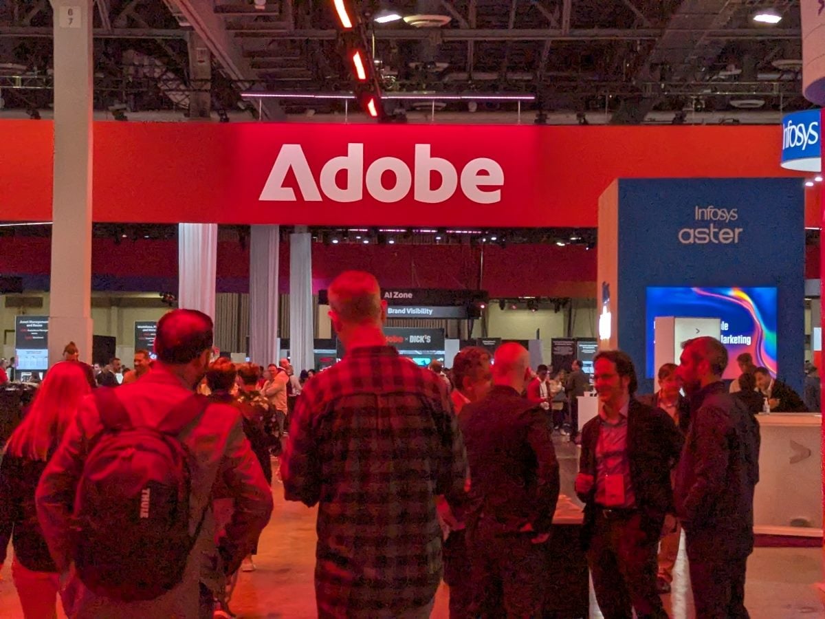 Attendees in front of a large Adobe sign at the Adobe Summit in the vendor hall in April 2026 at the Venetian in Las Vegas.